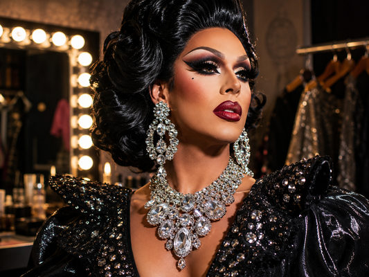 Drag queen frente al espejo con pendientes brillantes, collar de pedrería, pulseras y accesorios de escenario.
